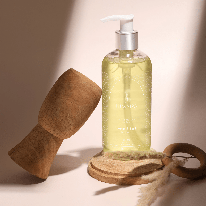 Product shot of tan brown color hand wash bottle with pump, styled on round wooden stands and a ring with gentle studio lighting.